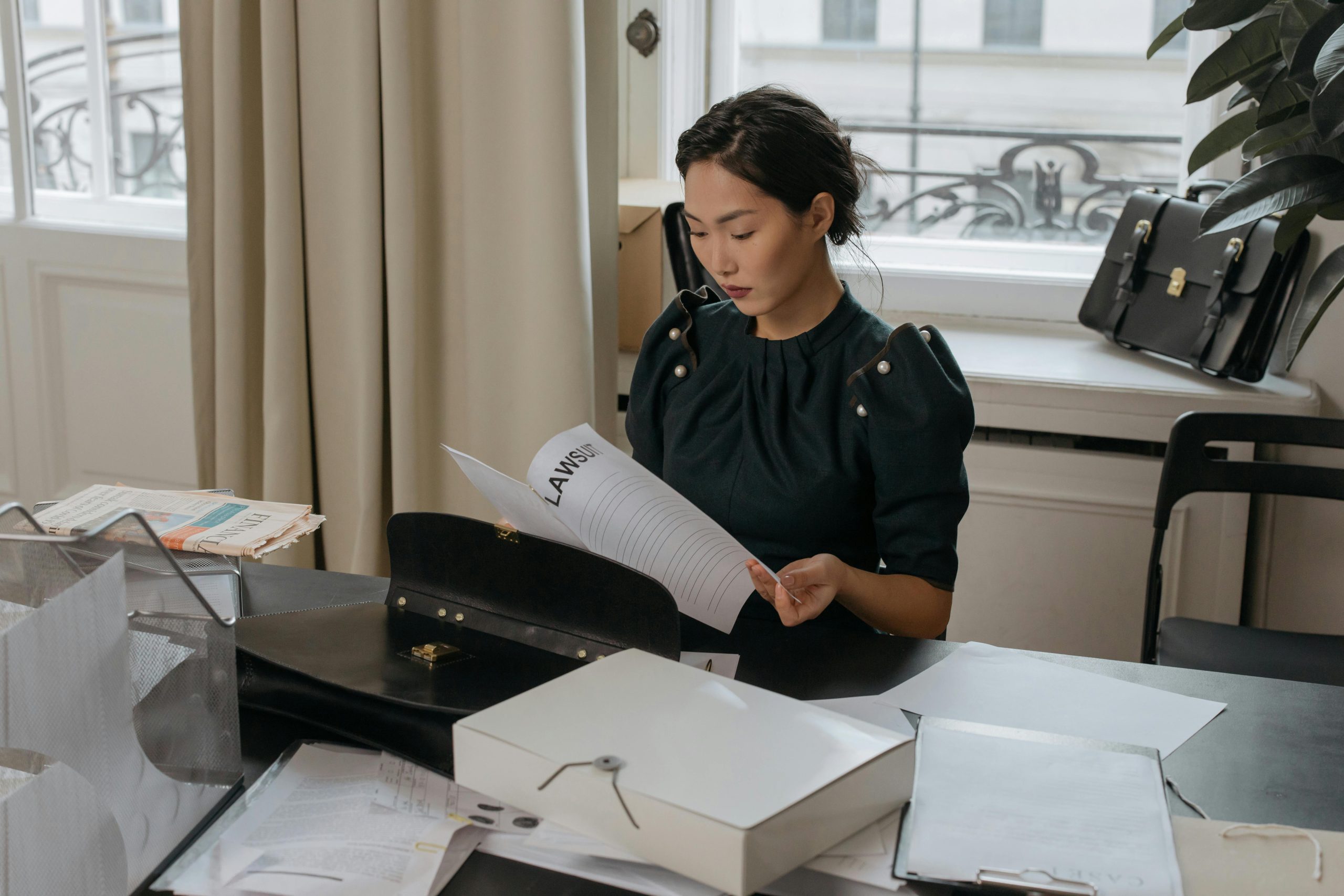 Asian woman sitting at a desk reading paperwork