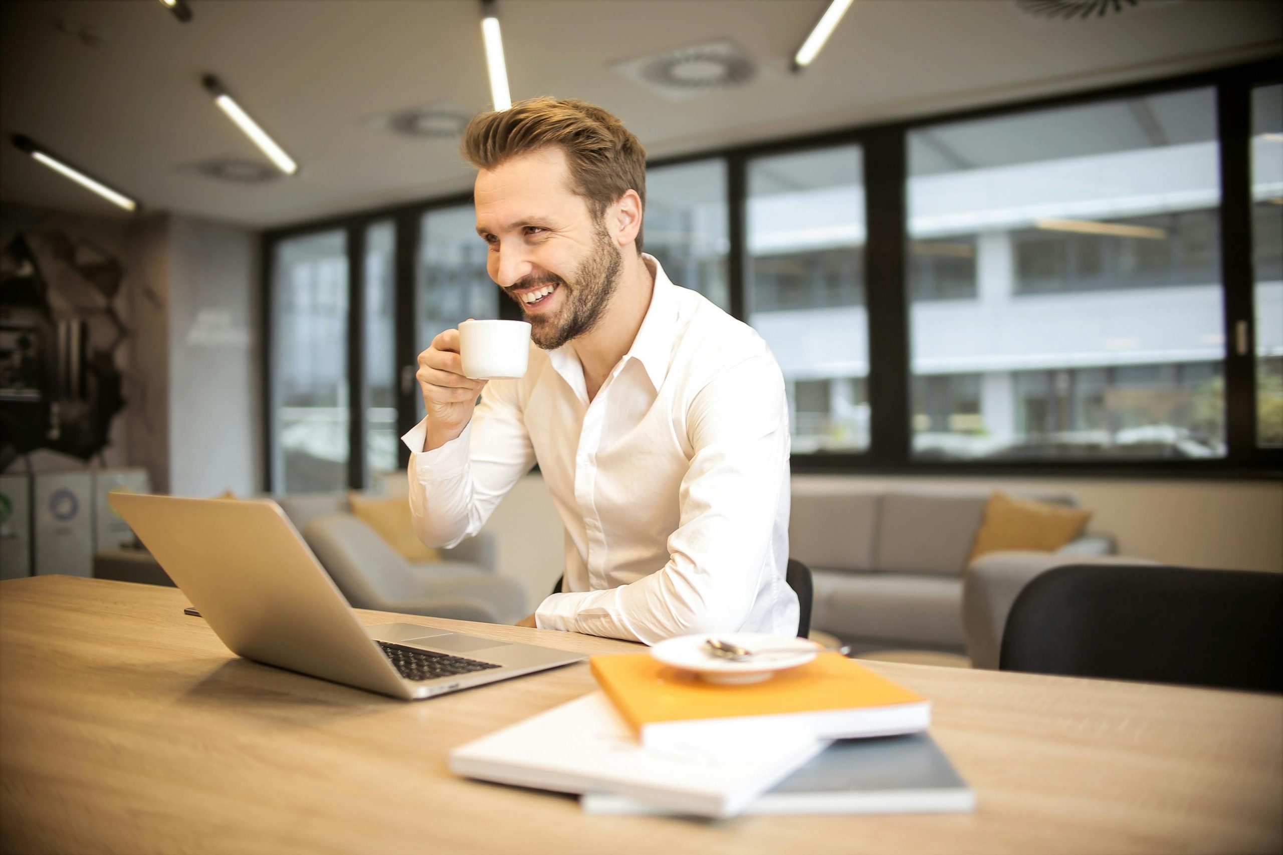 White man drinking coffee with a laptop and notebook