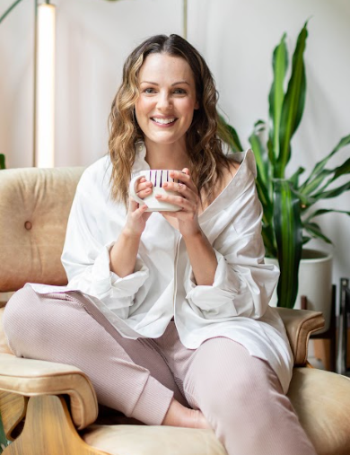 Smiling woman sitting comfortably with a cup of coffee, embracing calmness