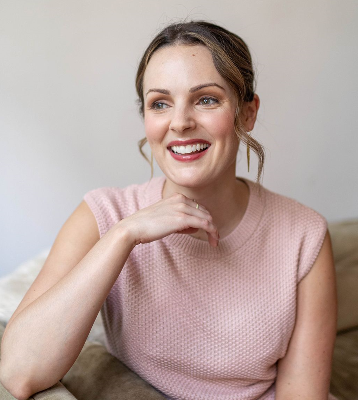 Smiling woman in a pink top, radiating confidence and warmth indoors