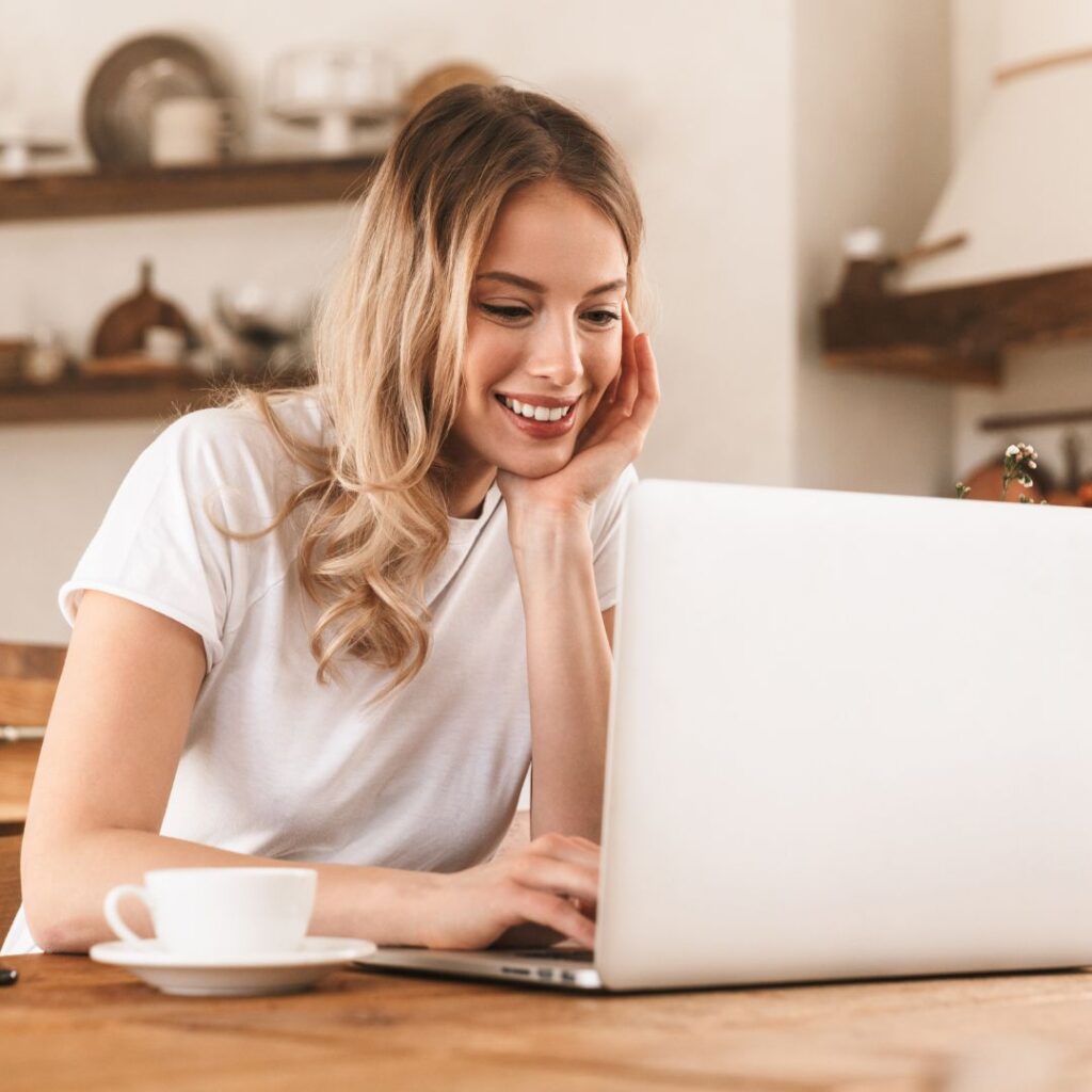 Woman Smiling and Working on Laptop